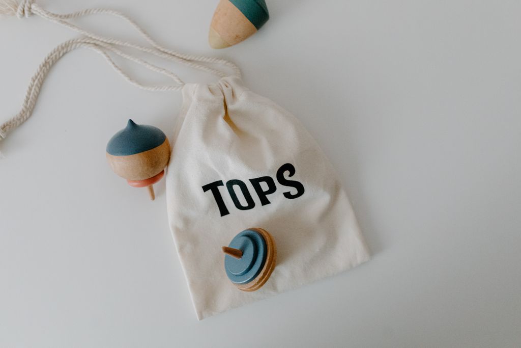 Woodworking Classes a minimalist photo of wooden spinning tops and a cloth bag labeled tops. perfect for toy and lifestyle themes. 7123055